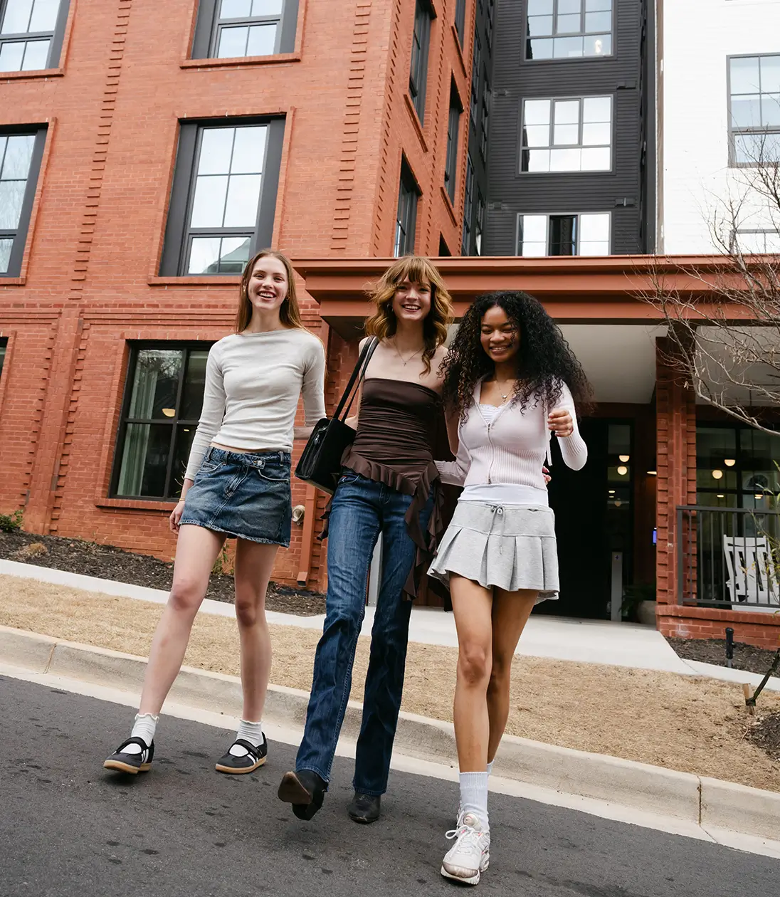 a group of young women walk outside their apartment complex