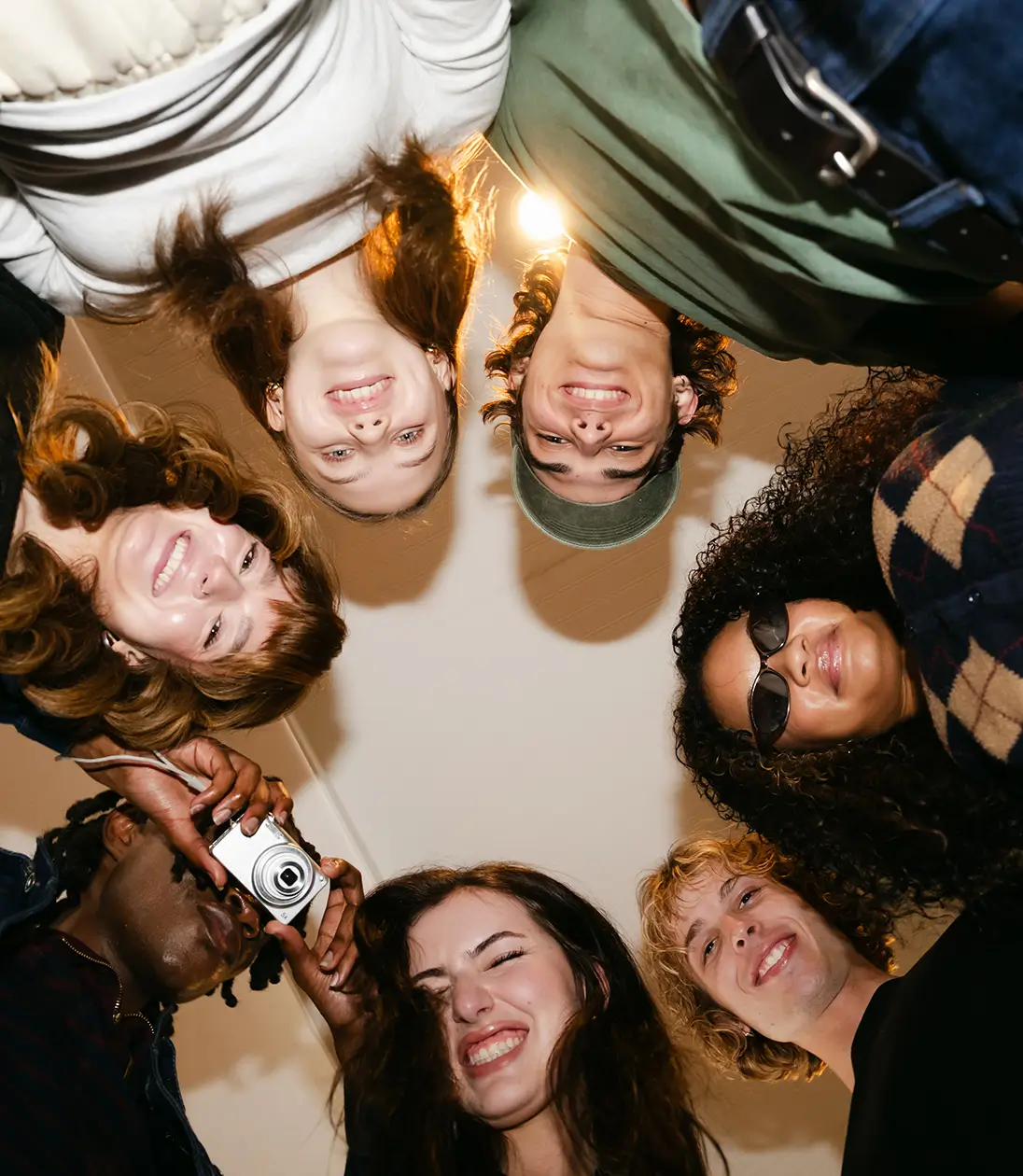 a group of young adults smile and look down at the camer