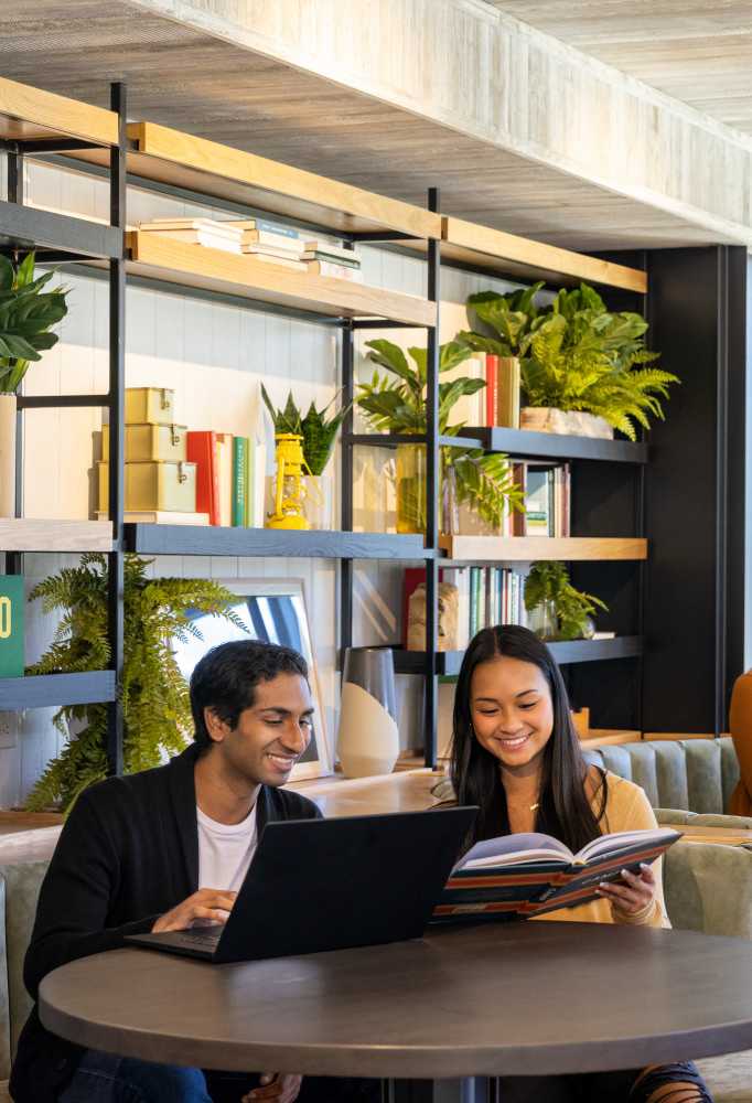 Two friends smiling and looking at a book