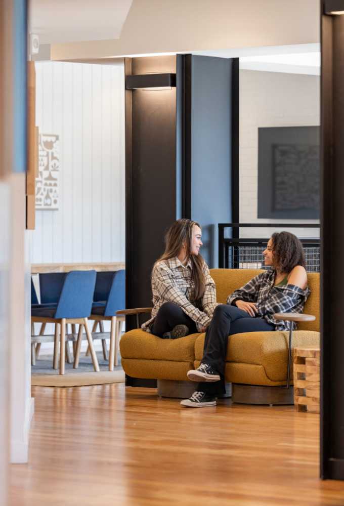 Two women talking and smiling on a couch