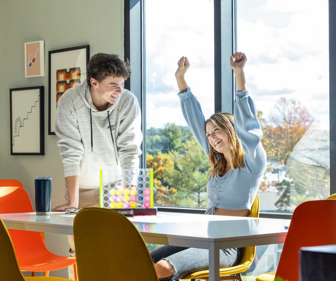 A woman cheering while playing Connect Four