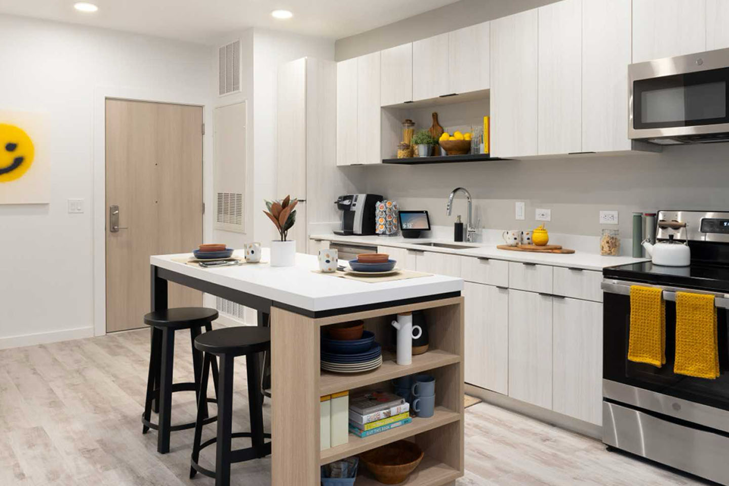 Kitchen with stainless steel appliances, barstool seating, an island, white cabinets, and built-in shelving.
