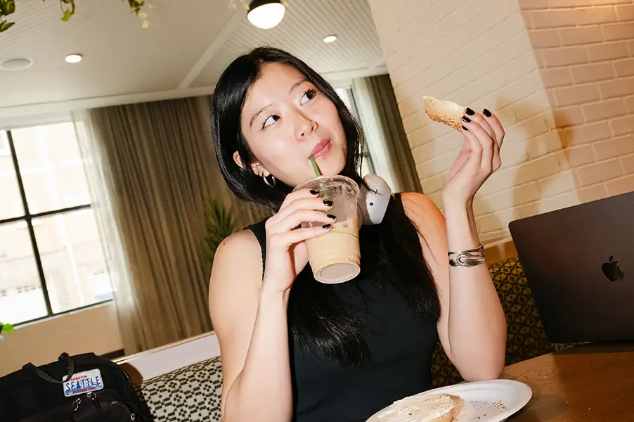 young woman enjoying a bagel and ice coffee