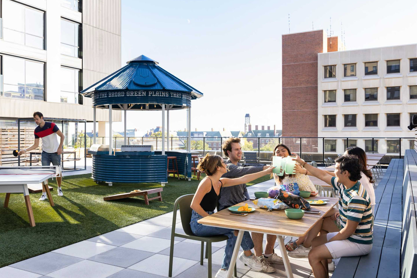 Group of people sitting outside cheering drinks, eating chips, all in an comfortable outdoor environment.