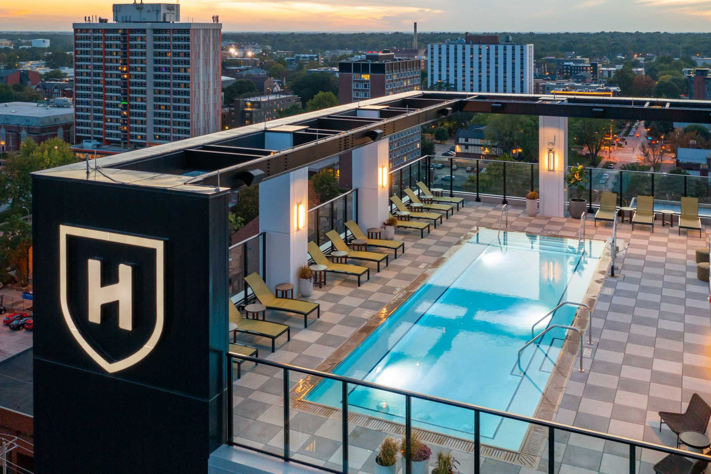 Rooftop pool with chairs surrounding it and scenic views.