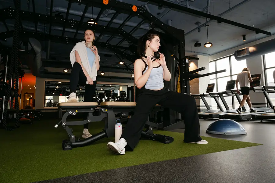 two young women mid exercise in an apartment gym