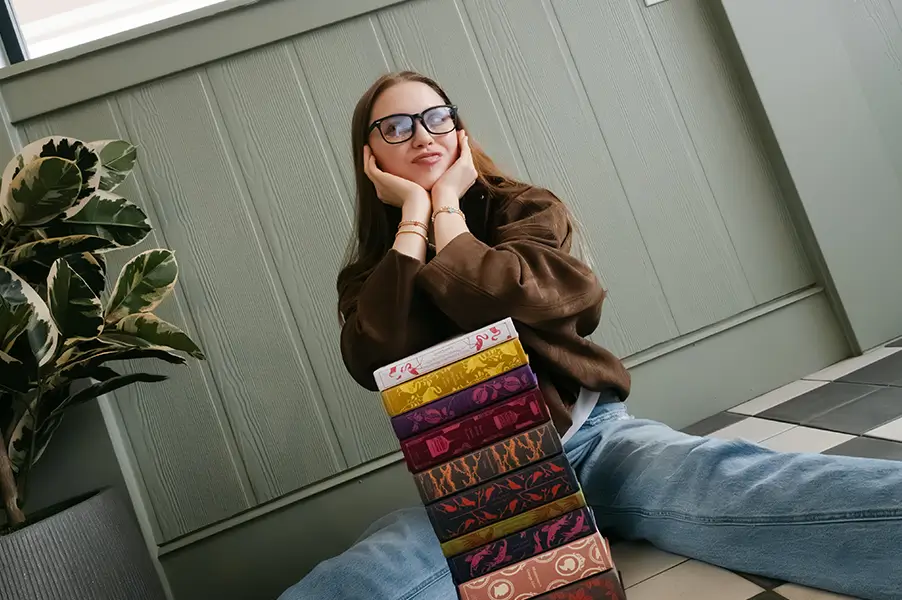 a woman poses with a stack of decorative books