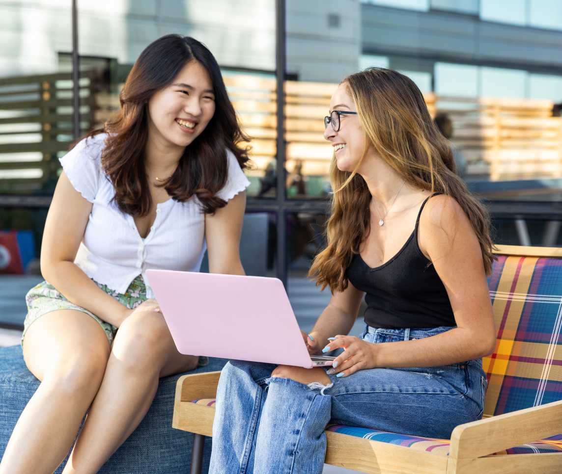 Two women smiling with a pink laptop