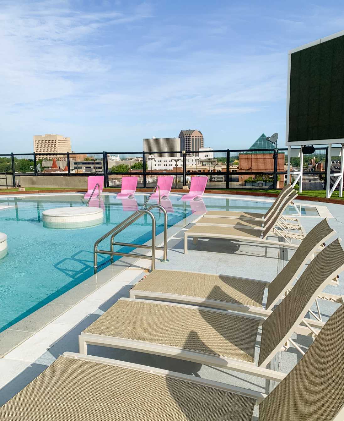 A swimming pool next to tan poolside chairs