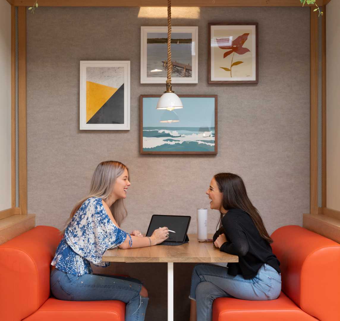 Two women talking while sitting in orange seats