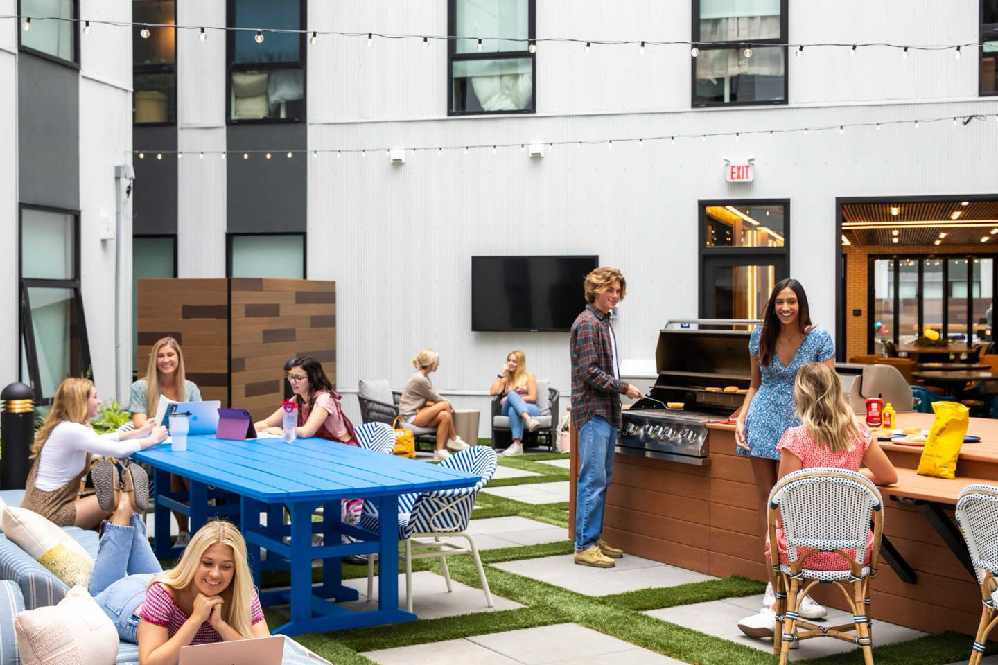 Outdoor lounge with young adults socializing and grilling