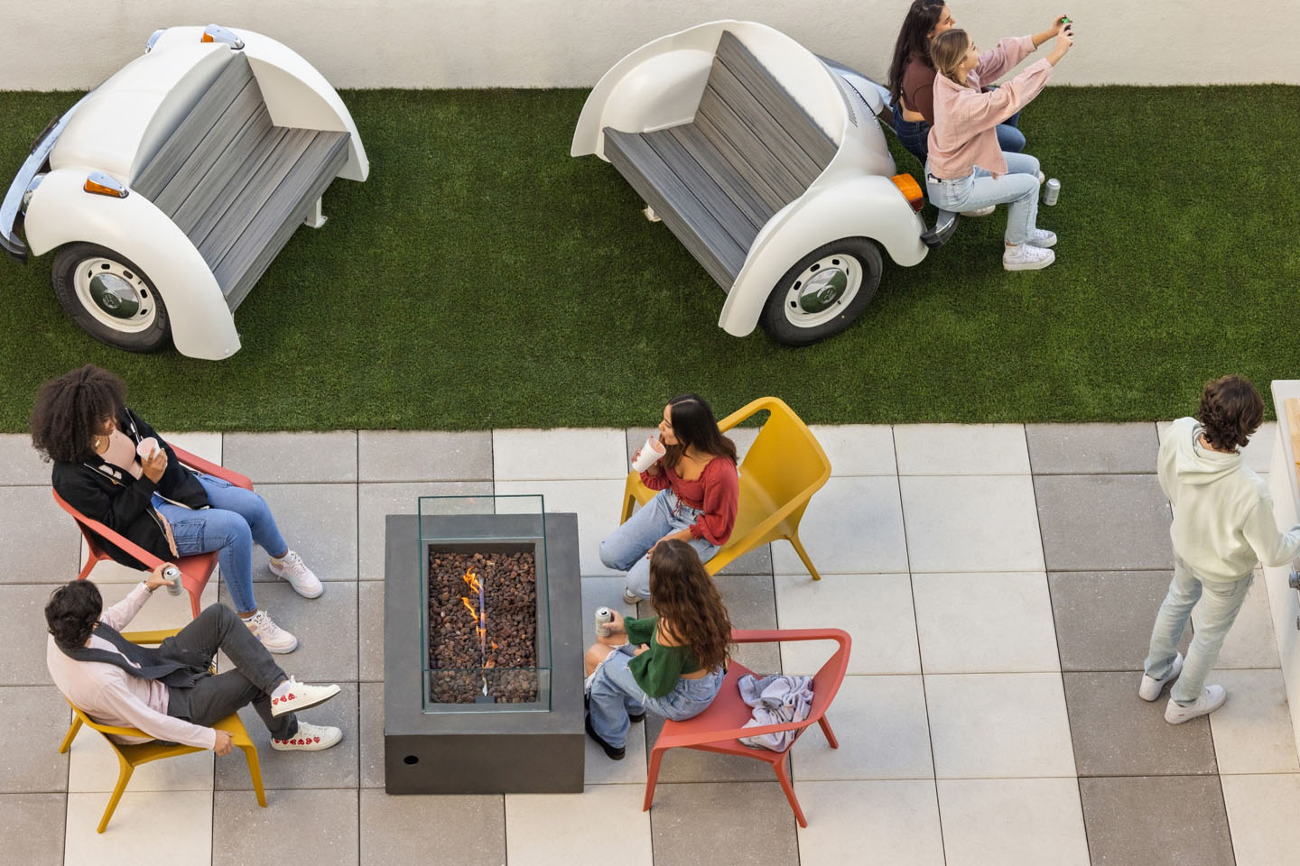 Young adults lounging outdoors by a fire pit.