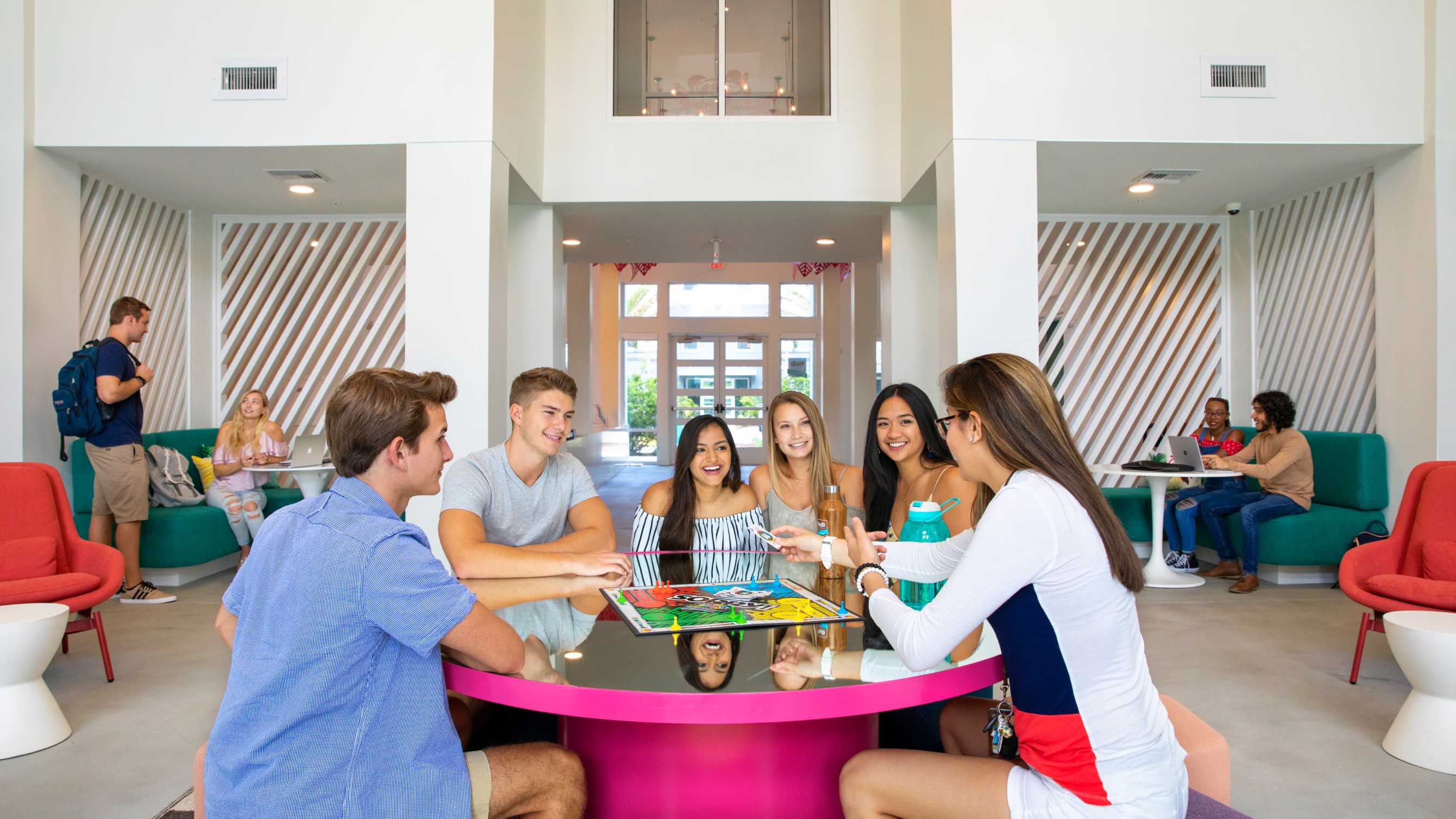 Group of friends smiling around a pink table