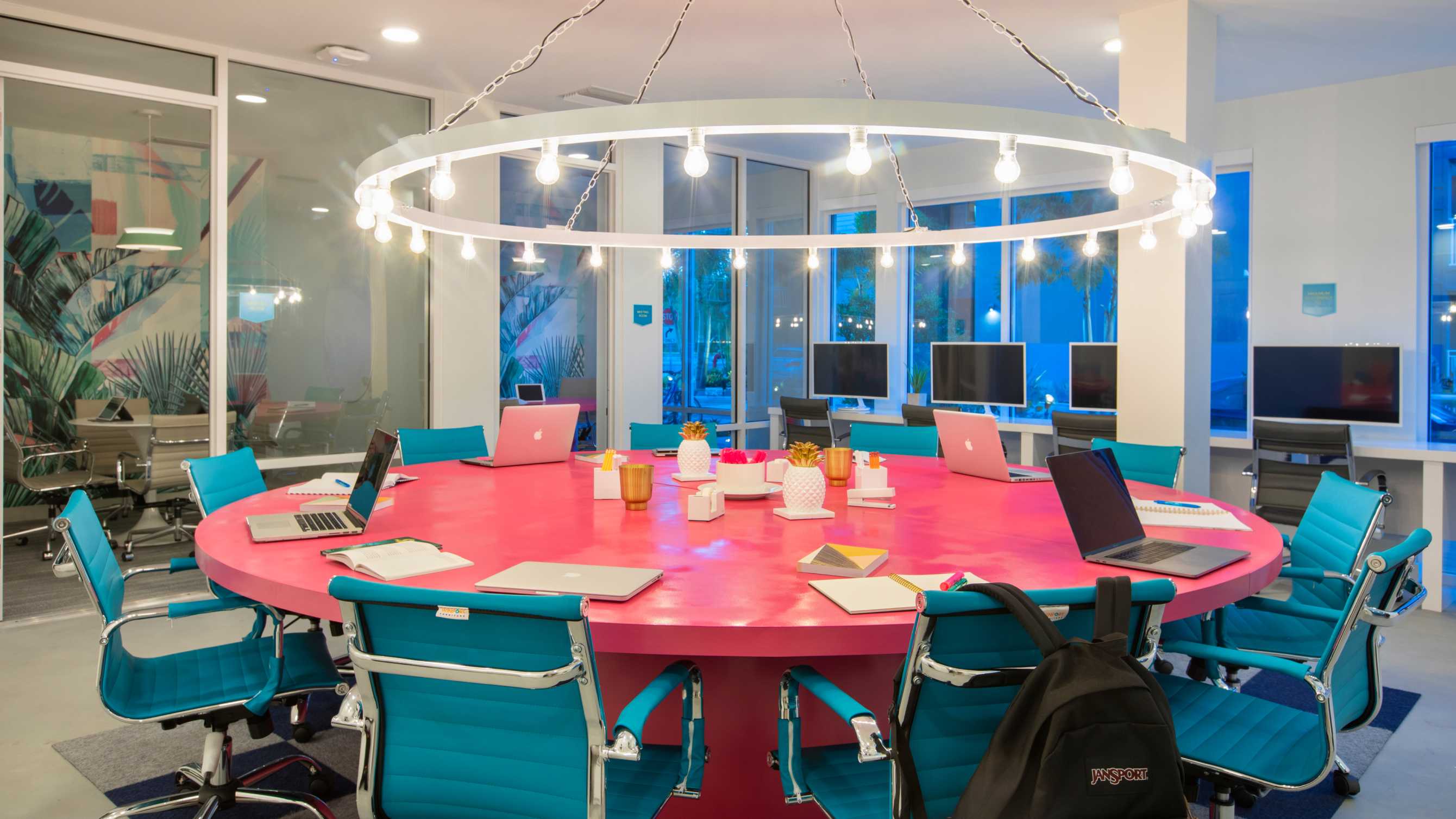 Circular pink table surrounded by teal chairs