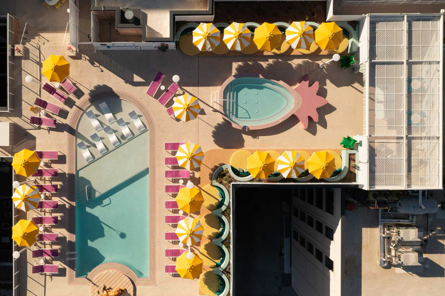 Spacious pool and a pineapple-shaped hot tub surrounded by pink chairs and yellow umbrellas.