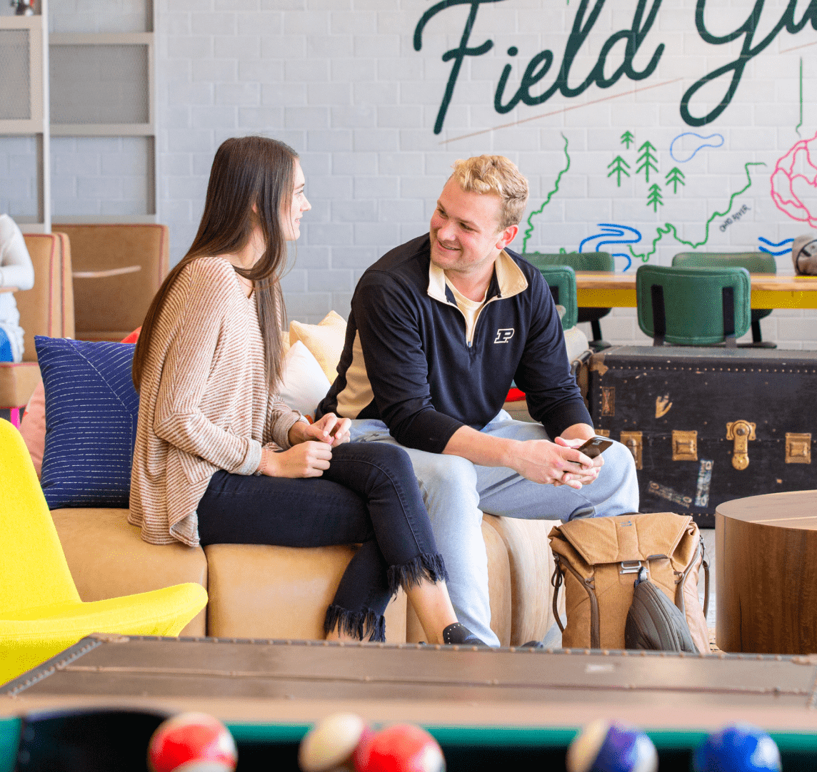 Two people talking and smiling near a pool table